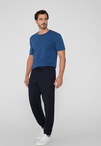 Camiseta de algodón azul de manga corta combinada con pantalones de chándal azul marino con cordón y zapatillas blancas. El conjunto presenta un corte relajado y una textura suave.