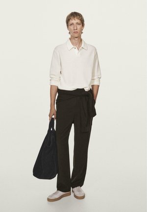 Weißes Langarm-Polo, schwarze weite Hose mit gebundenem Bund, marineblaue Tragetasche und weißeSneaker mit beigen Sohlen. Minimalistisches Design.