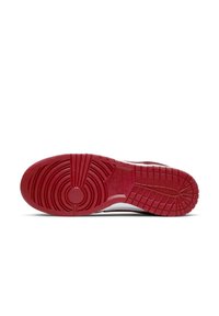 Red rubber outsole with textured grip pattern, featuring circular and linear grooves. Notable Nike branding embedded in design.