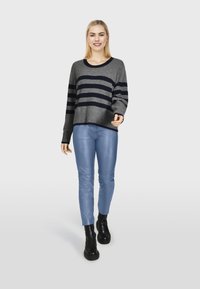 Grijze en marineblauwe gestreepte trui, losse pasvorm, met geribde manchetten; gecombineerd met lichte, lichtblauwe leren broek en chunky zwarte laarzen.