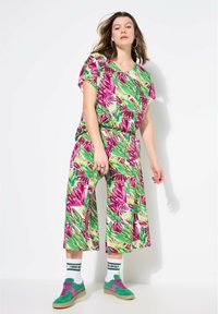 Conjunto multicolorido con estampado de hojas tropicales que presenta una blusa holgada y pantalones de pierna ancha, confeccionado en una tela ligera. Acentos en rosa brillante y verde.