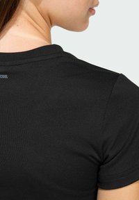 Crna majica kratkih rukava s okruglim izrezom i glatkom teksturom, koja ima "COOL" logotip na leđima blizu ovratnika.