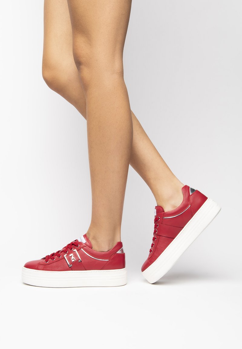 Sneaker platform in pelle rossa con suola in gomma bianca, punta rotonda e design con lacci. Accentuati da dettagli in argento sul tallone.
