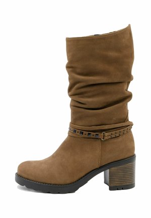 Botine din suede maro, cu partea superioară căzută, accent cu curea cu ținte și toc cu straturi. Textură netedă și design cu vârf rotunjit.