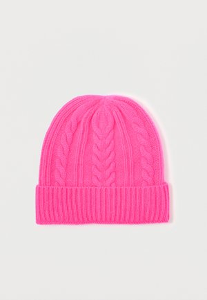 Cappello di lana lavorato a maglia di un brillante colore rosa, con motivi a treccia e un ampio risvolto a coste, steso su uno sfondo bianco.