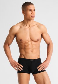 Boxer-briefs noirs en tissu doux, dotés d'une ceinture élastique avec un logo. Design ajusté, texture lisse, détails minimalistes.