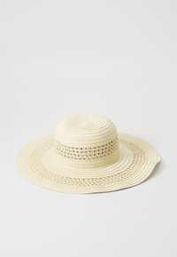 Sombrero de paja de ala ancha en color crema, con un tejido texturizado y recortes en forma de encaje a lo largo de la banda, con un diseño de corona suave y redondeada.