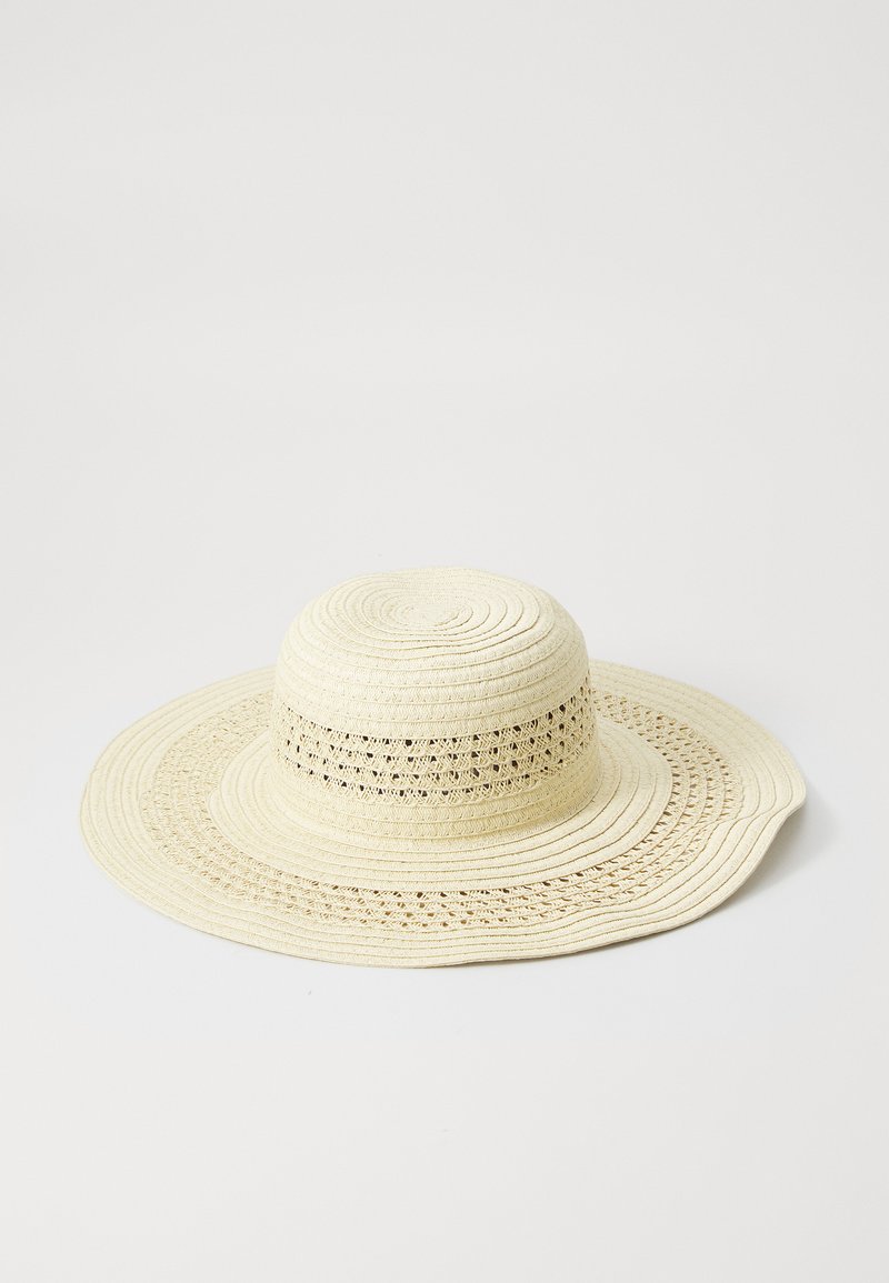 Sombrero de paja de ala ancha en color crema, con un tejido texturizado y recortes en forma de encaje a lo largo de la banda, con un diseño de corona suave y redondeada.