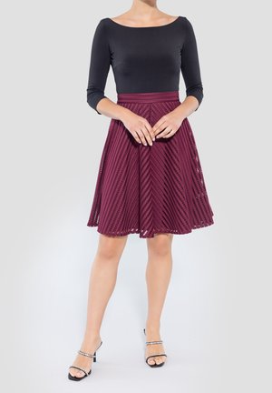 Sort langærmet bluse parret med en bordeaux A-line nederdel med teksturerede diagonale mønstre. Outfitet er fuldendt med sorte hæle sandaler.