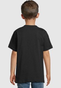 Černé bavlněné tričko s kulatým výstřihem a krátkými rukávy, zobrazené zezadu. Bez ozdob, žádné viditelné logo ani vzory. Volné střih.