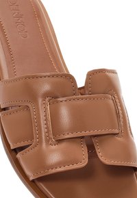 Sandalia de cuero color coñac tipo slip-on con tiras anchas entrelazadas y cosidas, y plantilla acolchada, diseñada para uso casual.