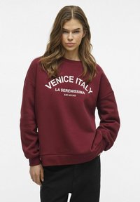 Felpa color bordeaux con testo bianco che dice "VENEZIA ITALIA LA SERENISSIMA EST. 421DC." Presenta un collo rotondo e una vestibilità rilassata.
