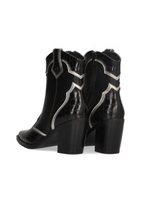 Botas de vaquero negras con textura de cocodrilo, acentos plateados y un diseño curvado. Cuentan con un tacón cuadrado medio y cierre de cremallera.