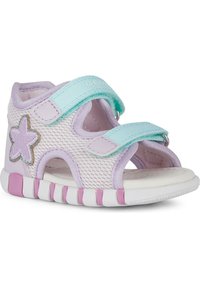 Sandalias de malla morado claro con una correa ajustable color teal, acento de estrella plateada y una suela blanca que presenta rayas rosas y blancas.