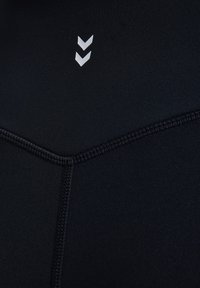 Czarna tkanina sportowa o gładkiej fakturze, z białymi akcentami w zygzak. Szczegóły szwów są obecne w całym projekcie.