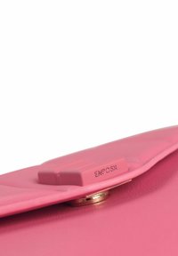 Clutch in pelle rosa con una texture liscia, caratterizzata da una chiusura a scatto prominente e un logo impresso. I bordi stondati completano il design.