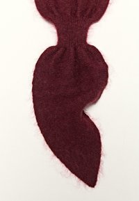 Tessuto a maglia bordeaux con una texture morbida e pelosa, caratterizzato da una forma unica e asimmetrica che si affina verso un'estremità punta.