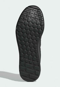 Sort skosål med en tekstureret overflade med cirkulære greb og en let krumning. Bemærkelsesværdig branding "STEALTH" nær hælen.