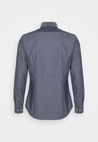 Šedá košile s dlouhým rukávem a zapínacími manžetami, s upraveným střihem a tmavší textilní panelem na horní části zad.