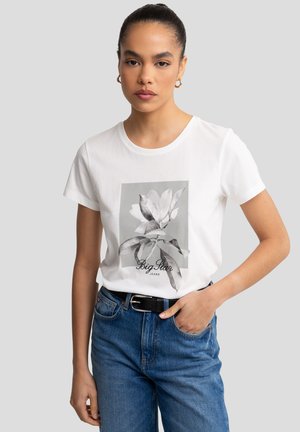Bílý bavlněný tričko s šedým květinovým potiskem a nápisem "Big Star Jeans" pod ním. Stylizováno s modrými džíny a černým opaskem.