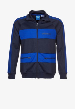 Veste zippée pour homme en polyester bleu marine avec des rayures horizontales bleues. Elle présente un logo brodé, des poches zippées et des poignets côtelés.