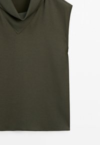 Top senza maniche di un verde oliva scuro, caratterizzato da un scollo a V e una texture liscia. Design semplice con orlo dritto e senza ulteriori accenti.