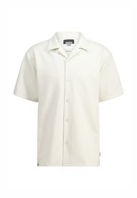 Lyhythihainen, kermavärinen paita, jossa on tekstuurikuvio, nappisuljenta edessä ja klassinen kaulus. Brändilogo näkyvissä kauluksen sisäpuolella.