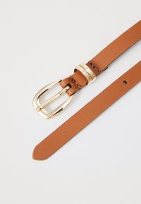 Cintura in pelle color cuoio con fibbia in metallo dorato. Presenta una texture liscia e fori regolabili per adattarsi alle misure. Decorata con dettagli di cucitura.