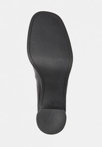 Semelle de chaussure noire avec une surface en caoutchouc texturé, dotée d'une prise à motif et d'un talon arrondi lisse, conçue pour la stabilité et l'adhérence.