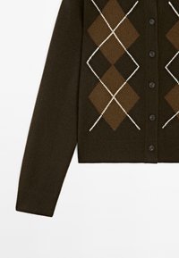 Cardigan boutonné marron foncé à manches longues avec un grand motif losanges en marron clair et blanc sur le devant.