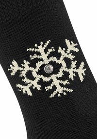 Czarna skarpetka z białym wzorem śnieżynki, wykonana z teksturowanego materiału dzianinowego, z srebrnym detalem w postaci logo na środku.