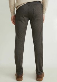 Šedé texturované kalhoty s úzkým střihem, s dvěma zadními kapsami a tmavým pasem. Kombinovány s hnědou obuví.