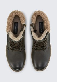 Brązowe skórzane botki za kostkę z puszystym beżowym wykończeniem, okrągłym noskiem, sznurowanym przodem i zapięciem na zamek z boku. Teksturowana powierzchnia zewnętrzna i kontrastowe akcenty.