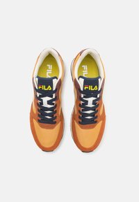 Sneakers i orange och brunt av blandade material med marinblå snören, vita accenter, vadderade innersulor och Fila-logotyp på tungan och innersulan.