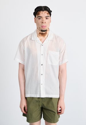 Short-sleeved, button-up shirt in sheer white fabric with narrow vertical stripes and a chest pocket, paired with olive green shorts.