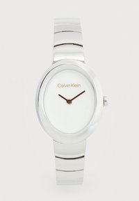 Γυναικείο ασημένιο μεταλλικό ρολόι βραχιόλι Calvin Klein με οβάλ καντράν, λευκό καντράν, μινιμαλιστικό σχέδιο και μαύρα δείκτες ώρας και λεπτών.
