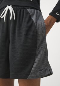 Bañadores deportivos negros con tejido de malla transpirable. Cintura elástica con cordones blancos, paneles laterales grises y pequeño detalle de logotipo.