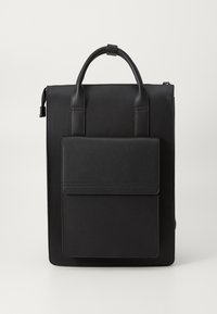 Mochila de cuero negra con un diseño minimalista. Cuenta con un asa en la parte superior, correas ajustables y un bolsillo frontal con cierre de solapa. Textura suave.