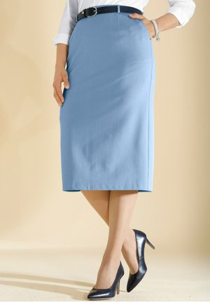 Jupe crayon bleu clair en tissu lisse, avec une coupe ajustée, portée avec des talons hauts bleu foncé.