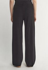 Czarne spodnie o szerokich nogawkach wykonane z miękkiego materiału o gładkiej strukturze, z wygodnym paskiem w talii i prostym, minimalistycznym designem.