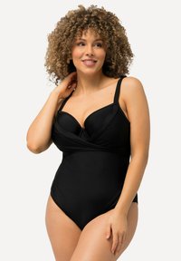 Maillot de bain une pièce noir avec soutien-gorge à armatures, design avant torsadé, bretelles ajustables, texture lisse et ouvertures de jambe très échancrées.