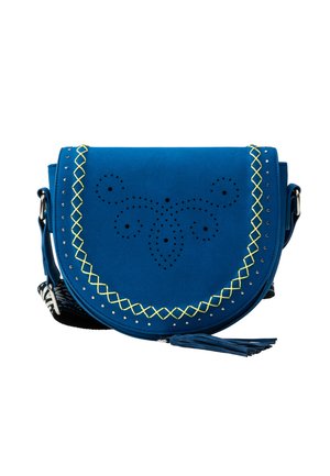 Blå crossbody taske med gul zigzag syning, cirkulært perforeringsmønster, sølv nitter og en kvast på frontklappen.