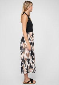 Robe maxi avec un haut noir et une jupe fluide arborrant des motifs abstraits marron, noir et crème. Texture lisse, design sans manches.
