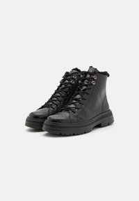 Black high-top boots with a crocodile texture, featuring a lace-up design, metal eyelets, and a textured rubber sole. Soft lining at the top.