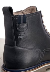 Schwarze Leder-Ankle-Boots mit einem Wildlederfutter, ausgestattet mit einem GORE-TEX-Label, kontrastierenden Schnürsenkeln und einem markanten gestreiften Zugtab. 