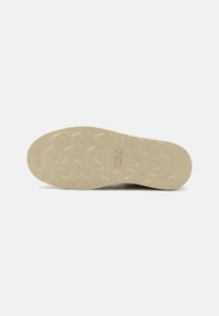 Suela de zapato de goma beige con un patrón texturizado en zigzag. "JACKS JONES" está grabado en el centro.