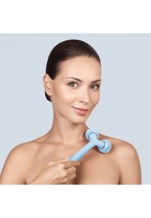 Kvinde med glat hud bruger en blå dobbeltkugle ansigtsrulle på sin skulder mod en lysegrå baggrund.