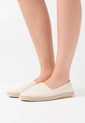 Vita flätade canvas slip-on skor med en strukturerad yta och ljusbeige sula, med rund tå och sidogummiskär för enkel påtagning.