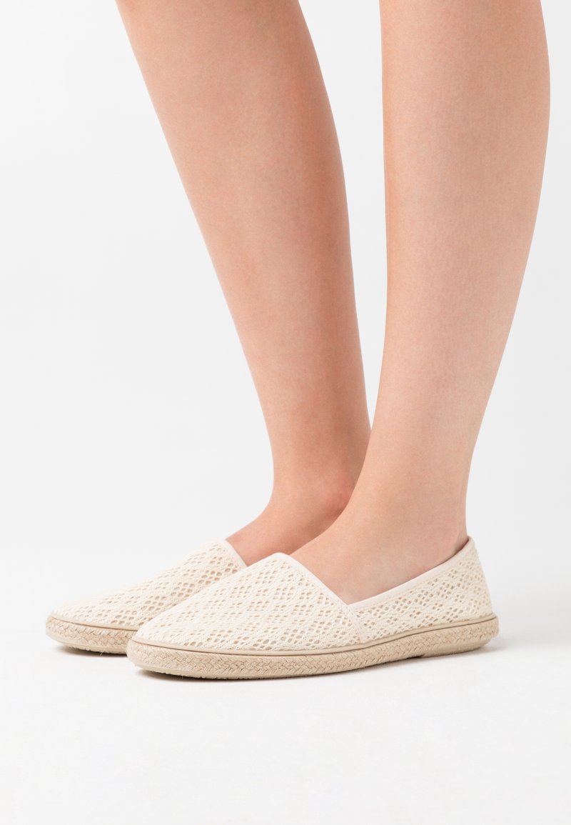 Bílé pletené plátěné slip-on boty s texturovaným povrchem a světle béžovou podešví, s kulatou špičkou a bočním elastickým páskem pro snadné obouvání.