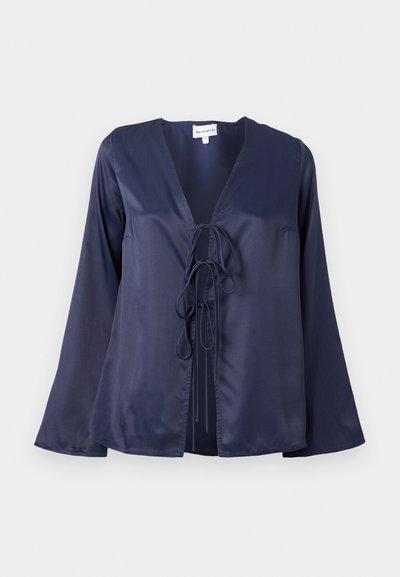 Blusa de satén azul marino con escote en V, mangas largas acampanadas y cierre de lazo en la parte delantera. Textura suave con un diseño sencillo y elegante.